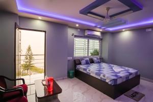 sypialnia z łóżkiem i oknem z fioletowymi światłami w obiekcie River Leaf Inn Taki w mieście Hāsnābād