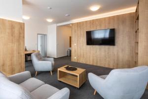 a living room with two chairs and a tv on a wall at Hotel Regent in Třeboň