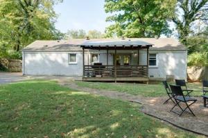 a house with a porch and two chairs in a yard at The Pennington - Roomy Dog-friendly Home with Yard in Nashville