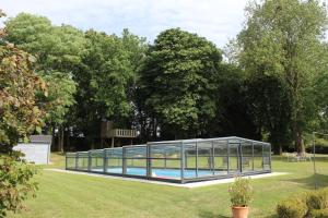 a glass house with a swimming pool in a park at Au bois Noël - Le Cerisier in Lescherolles