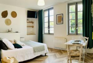 a bedroom with a bed and a table and windows at Le Tropical - Studio avec terrasse in Angoulême