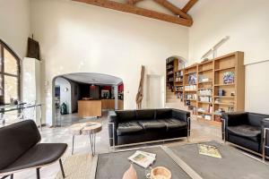 uma sala de estar com sofás de couro preto e uma mesa em La Casalissa em Flaux