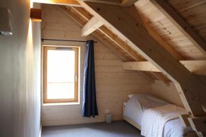 een bed in een houten kamer met een raam bij chalet montagne la lupina in Les Orres