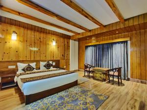 a bedroom with a bed and a table in a room at Hotel Vajra in Tawang