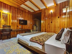 a bedroom with a bed and a desk and a television at Hotel Vajra in Tawang