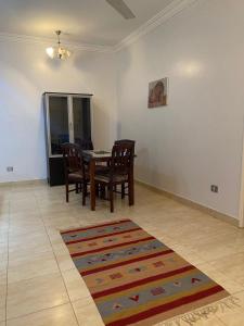a dining room with a table and chairs and a rug at Luxorya hotel apartment in Nag` Naqsha