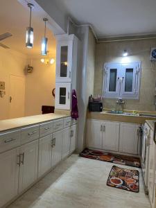 eine Küche mit weißen Schränken und einem Waschbecken in der Unterkunft Luxorya hotel apartment in Nag` Naqsha