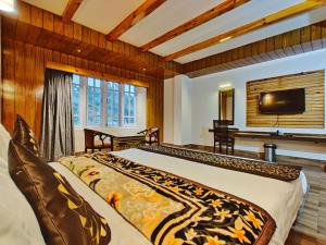 a bedroom with a large bed and a television at Hotel Vajra in Tawang