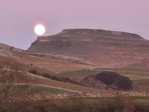 um pôr do sol no topo de uma colina com uma montanha em Robins Nest em Ingleton 