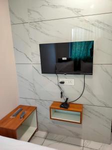 a flat screen tv on a wall in a bedroom at HOTEL JANTA INN in Vapi