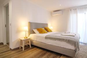 een slaapkamer met een groot bed met gele kussens bij Pine House - Faro Airport, Beach and City Center in Faro