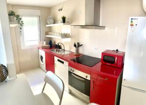 - une cuisine rouge avec évier et four micro-ondes dans l'établissement Apartamento Liru Bormujos 2, a 5 minutos de Sevilla, à Bormujos