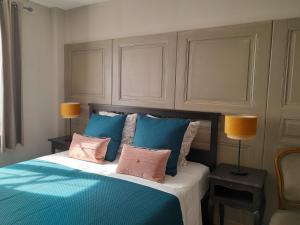 a bedroom with a bed with blue and pink pillows at La Mirabelle Gîte de charme in Mackenheim