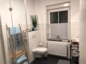 baño con aseo y ventana en Eresburg Apartment., en Marsberg