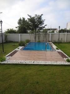una piscina en un patio con terraza de madera en Charm Ville - Villa with Nature in Hosur en Hosūr