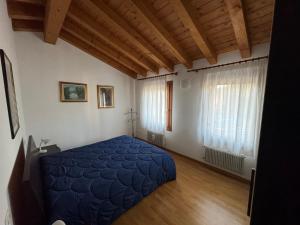 a bedroom with a blue bed and a window at Cà Maria - Appartamento Mansardato al primo piano in San Polo di Piave