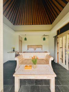 乌布Widya Luxury House的一间卧室，里面有一张床和一张摆着鲜花的桌子