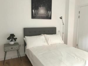 1 dormitorio con 1 cama con sábanas blancas y lámpara en Central Charm Dwelling, en Londres