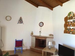 a living room with a fireplace and a clock on the wall at Monte da Palmeirinha in Vila Nova de Milfontes