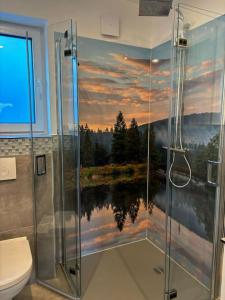 a bathroom with a shower with a painting of a sunset at Ferienhaus H-Auszeit in Fichtelberg
