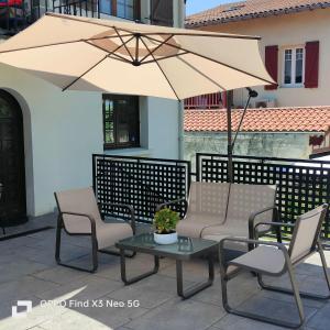 eine Terrasse mit Stühlen, einem Sonnenschirm und einem Tisch in der Unterkunft Marinela in Hendaye