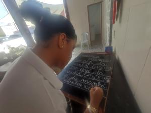 una mujer está escribiendo en una pizarra con escritura en ella en Pousada Santovo, en Porto de Galinhas