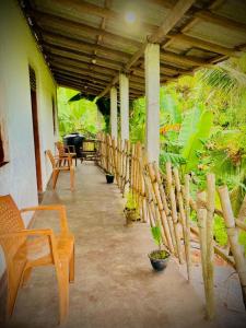 eine Veranda mit Stühlen und einem Zaun mit Pflanzen in der Unterkunft Obeisance in Tangalle