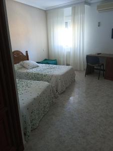 1 dormitorio con 2 camas, escritorio y ventana en EL ABAD en Abadía
