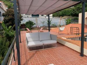 a white couch on a patio with a hammock at BnB BananaTree House in Arco da Calheta