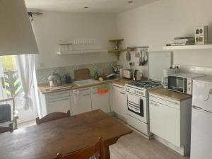 a kitchen with white appliances and a wooden table at Maison d'hôtes Petit Coin de Paradis in Moyon