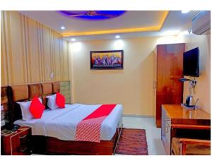 a bedroom with a bed with red pillows and a television at Hotel Highway, Udhampur in Udhampur