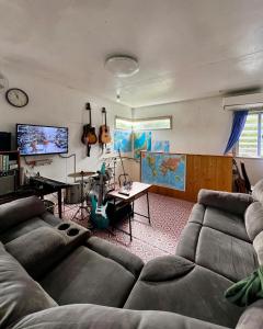 sala de estar con sofá y mesa en Holiday House Ryukyu-an "MUSIC HOSTEL", en Yomitan