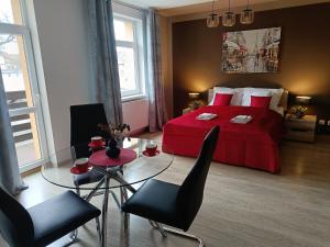 a bedroom with a red bed and a glass table at Apartamenty EDK in Jelenia Góra
