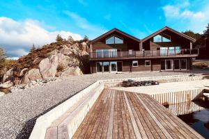 una casa en una colina rocosa con terraza de madera en Eksklusiv Rorbu - Havblikk 1 - Båtutleie en Bekkjarvik