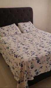 a bed with a blue and white blanket and pillows at casa entero piscina privada in Aparecida de Goiania