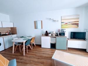 a kitchen with white cabinets and a table with chairs at T3 climatisé avec piscine et vue sur mer in Sète