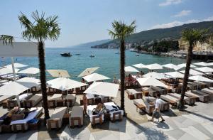 a view of a beach with people sitting in chairs and umbrellas at Sunflower Apartment in Opatija