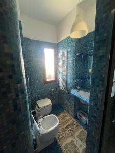 ein Bad mit einem WC, einem Waschbecken und einem Fenster in der Unterkunft CASA ZANON in Quattromiglio