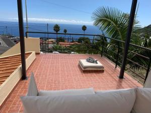 a balcony with a couch and a view of the ocean at BnB BananaTree House in Arco da Calheta
