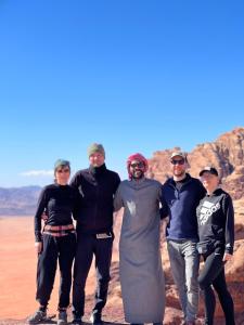 a group of people posing for a picture in the desert at desert colored camp in Wadi Rum