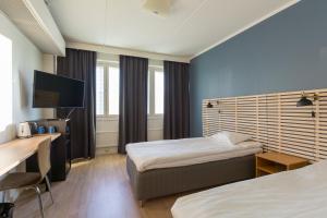 Habitación de hotel con 2 camas y escritorio en Torget Aparthotel, en Pori