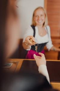 a woman is holding a pair of keys at Hotel Forsthof in Sankt Johann im Pongau