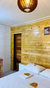 1 dormitorio con cama blanca y pared de madera en Pousada Maria Bonita Abreu e Lima en Maricota