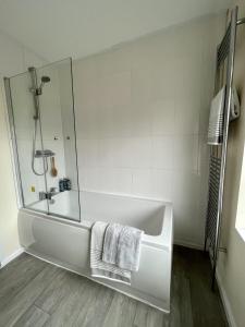 a white bathroom with a tub and a shower at CENTRAL, newly refurb 2 bed flat with FREE PARKING in Cambridge
