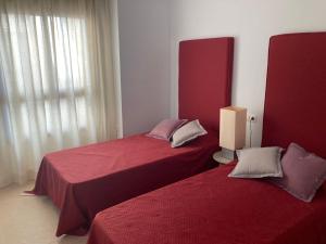 two beds in a room with red sheets at Atico Duplex Penthouse Rosa Marina Club Nautico Calpe Penon Sea view in Calpe +17 photos