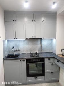 a kitchen with white cabinets and a sink at Lovely apartment in Tiraspol