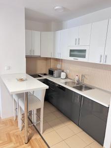 a kitchen with white cabinets and a sink and a table at Apartment 4th. Floor in Banja Luka