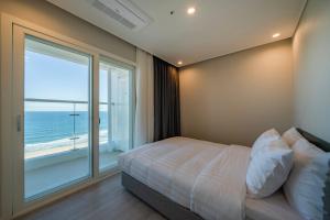 a bedroom with a bed and a large window at Le Bleu Naksan by Chestertons in Yangyang