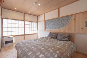 a bedroom with a bed in a room with windows at Private hot-spring Villa in Kusatsu in Kusatsu