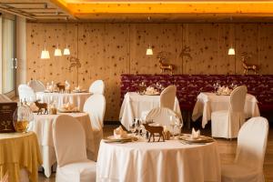 une salle à manger avec des tables et des chaises blanches dans l'établissement Hotel Emmy - five elements, à Fiè